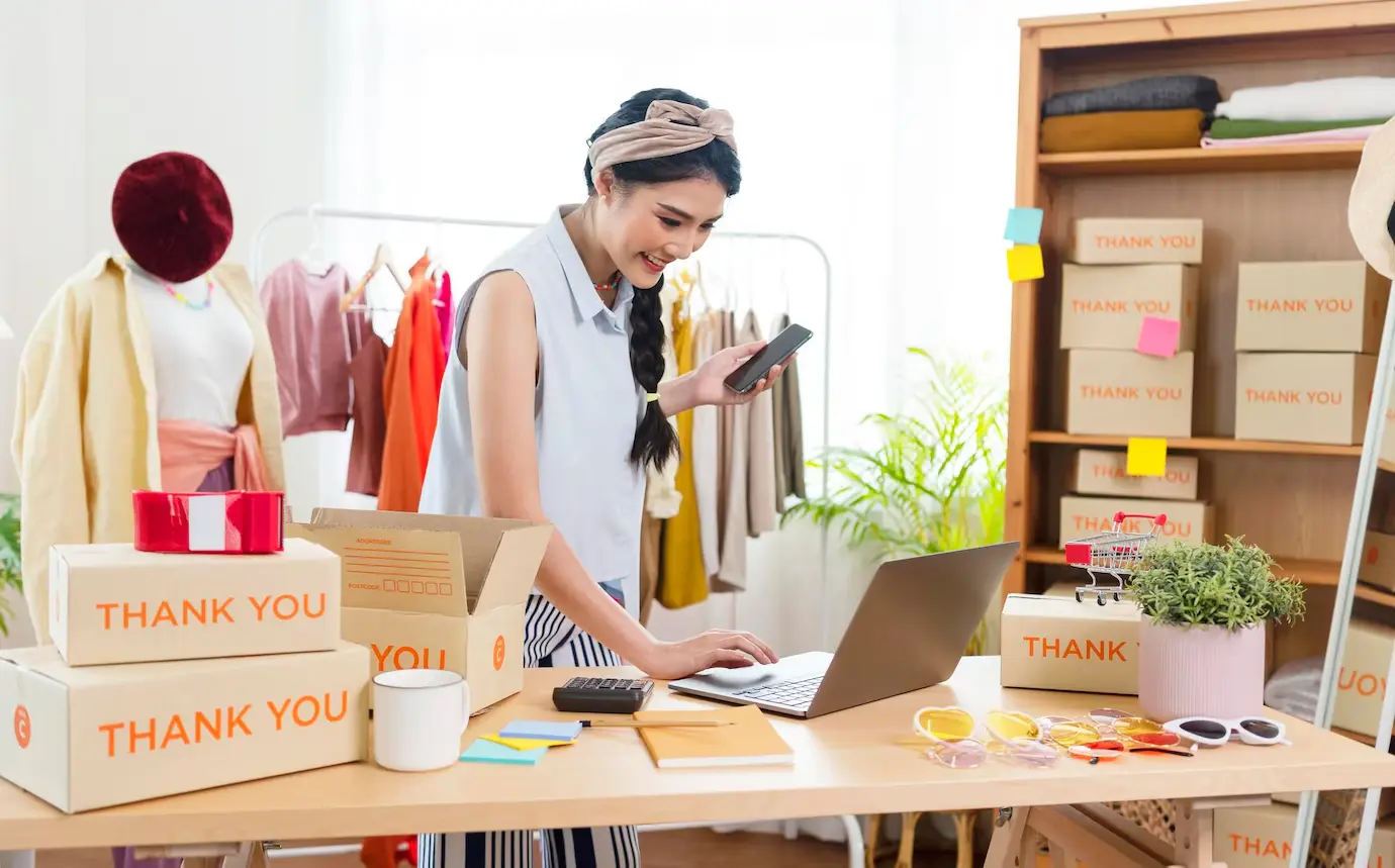 A person works on a laptop surrounded by shipping boxes labeled 