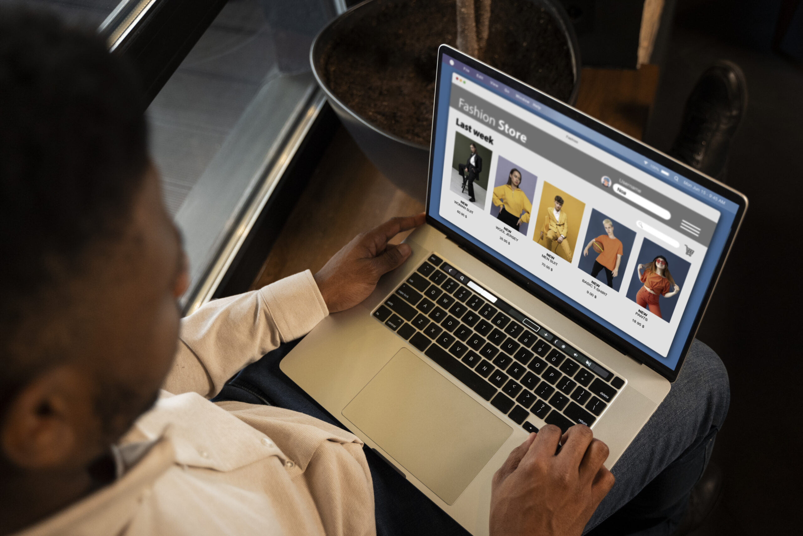 Person browsing an online fashion store on a laptop, viewing various clothing items displayed in a grid layout.