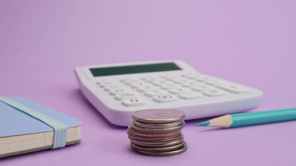 calculator, a stack of coins, a blue notebook