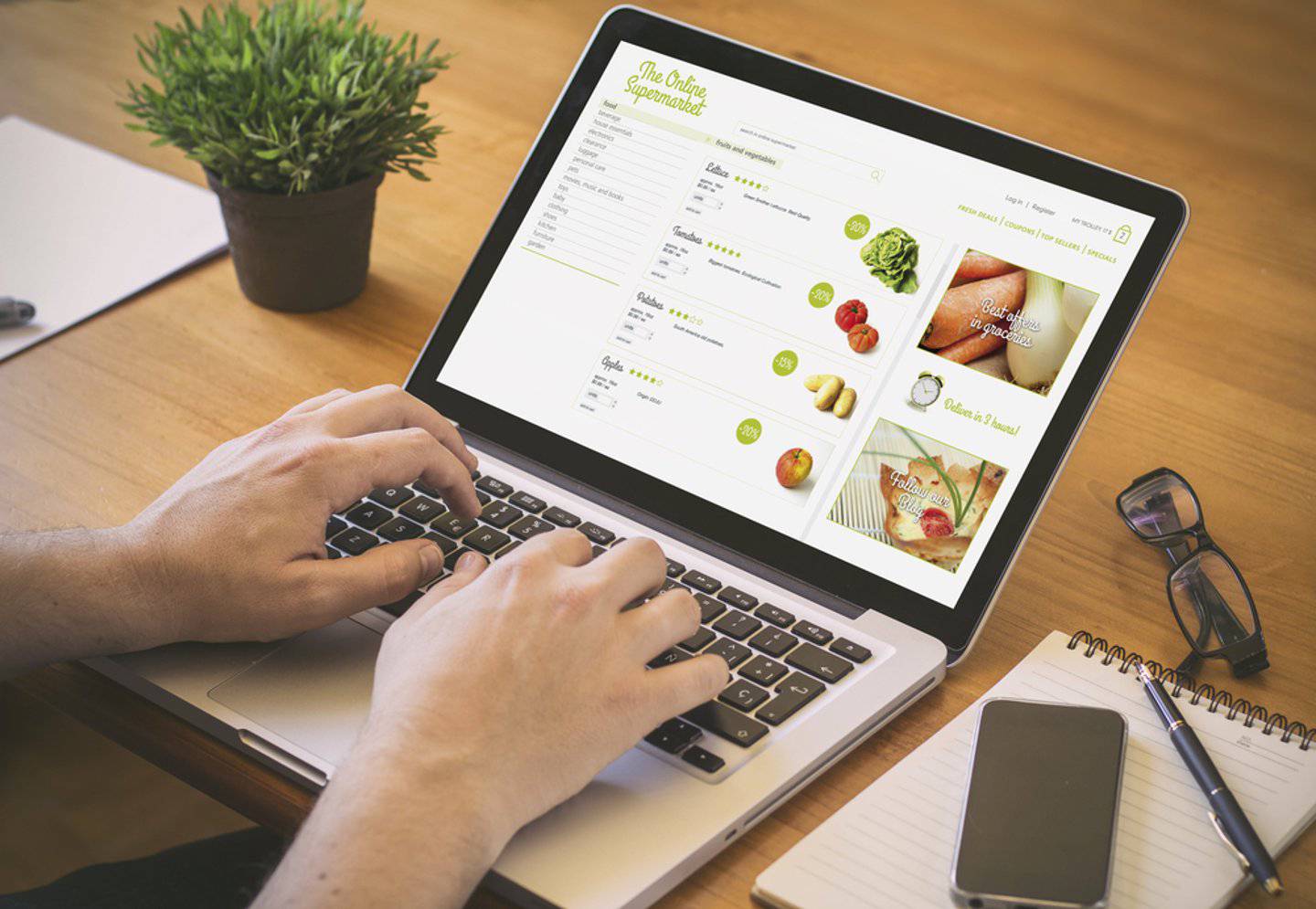 Close-up of hands typing on a laptop showing an online supermarket website